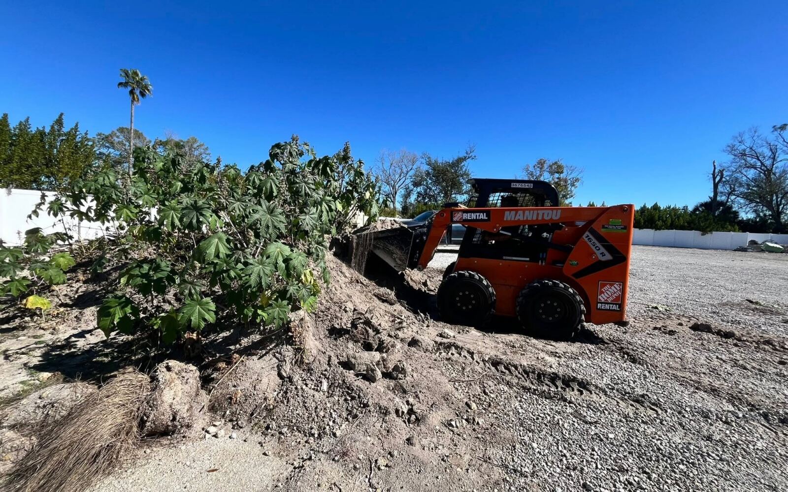 Skid steer clearing overgrowth from a lot
