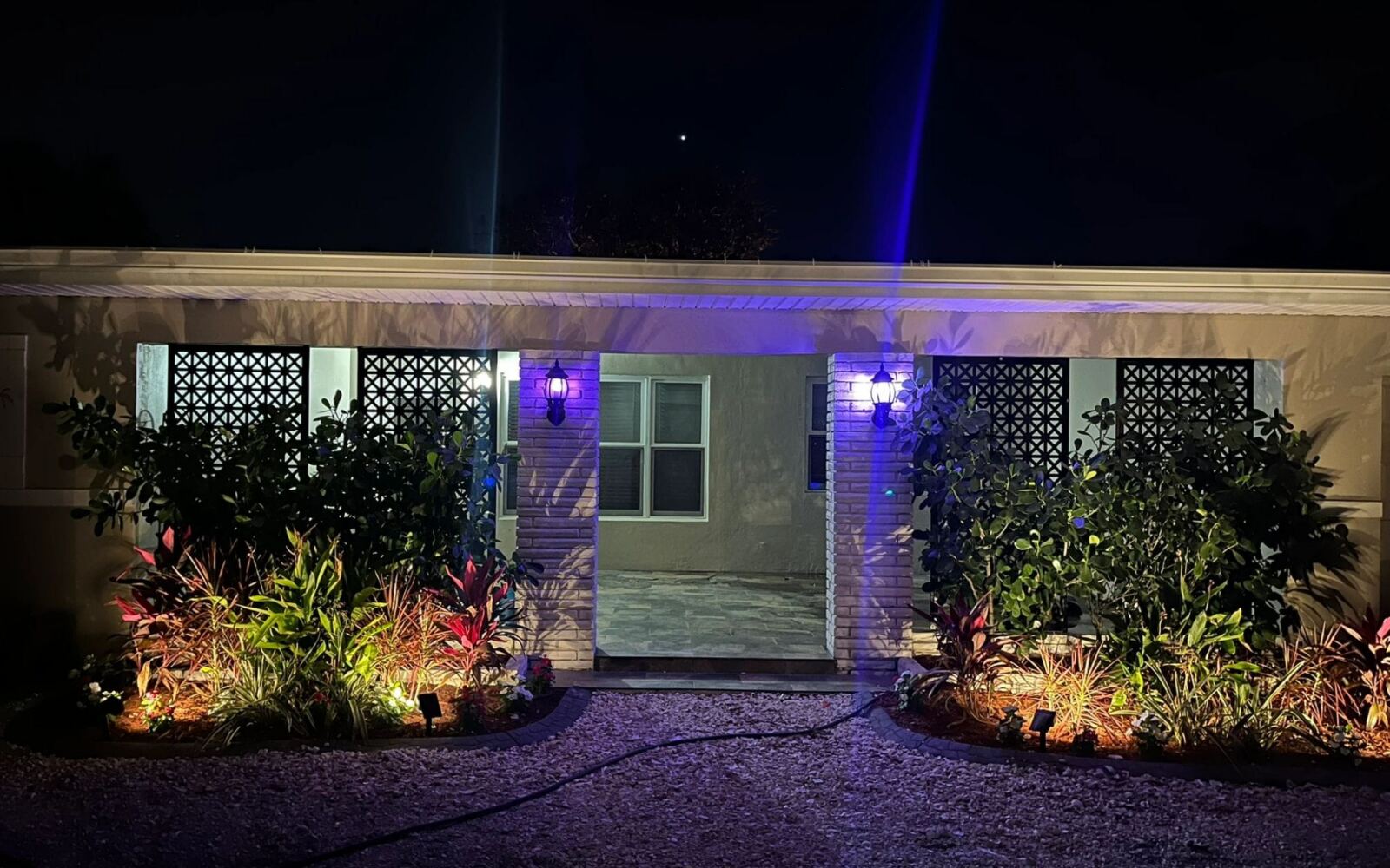 Low-voltage landscape lighting along a front planting bed at night