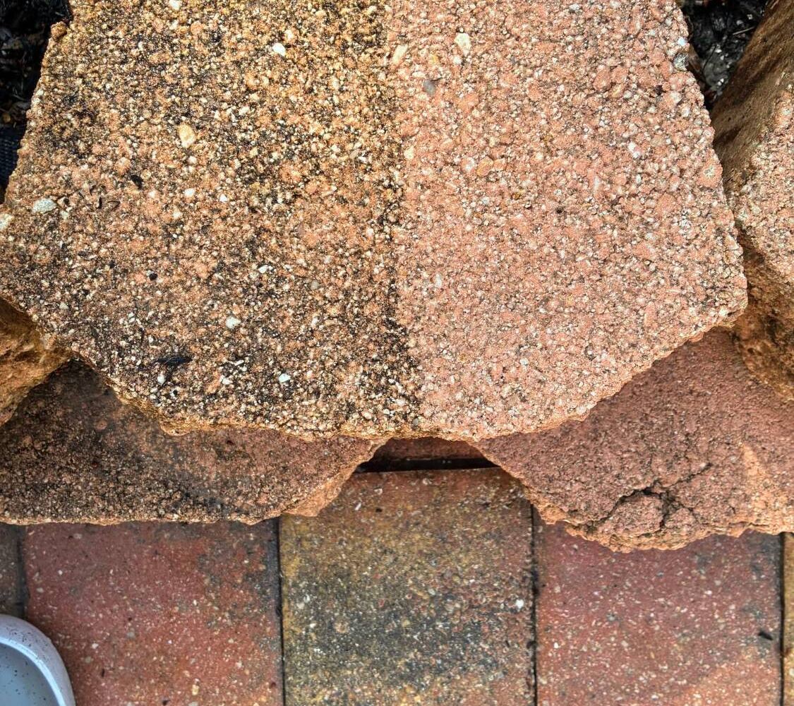 Retaining wall block half cleaned, showing before and after