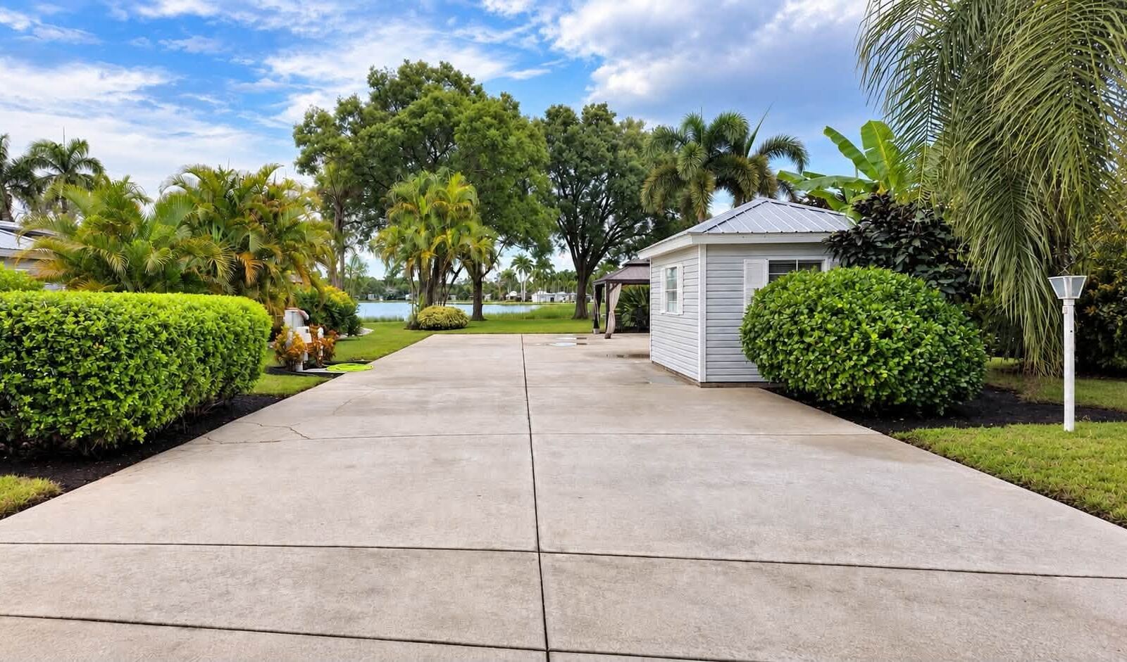After: washed concrete RV pad with trimmed hedges on both sides