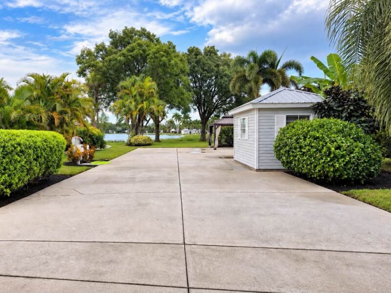 After: washed concrete RV pad with trimmed hedges on both sides