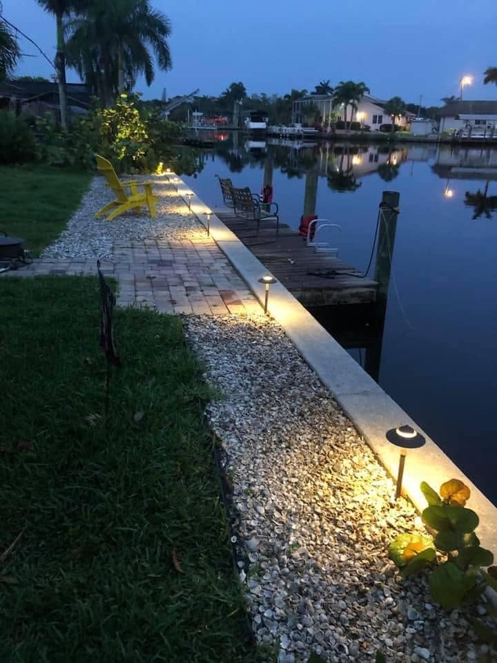 Path lights along a seawall shell border and paver walkway at dusk