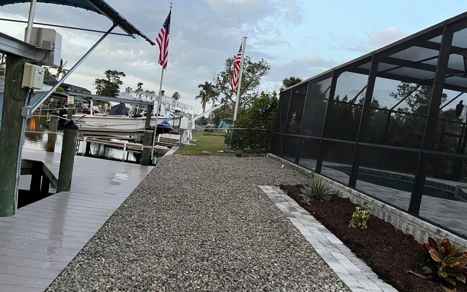 Rock border between a seawall and a pool cage, edged with pavers
