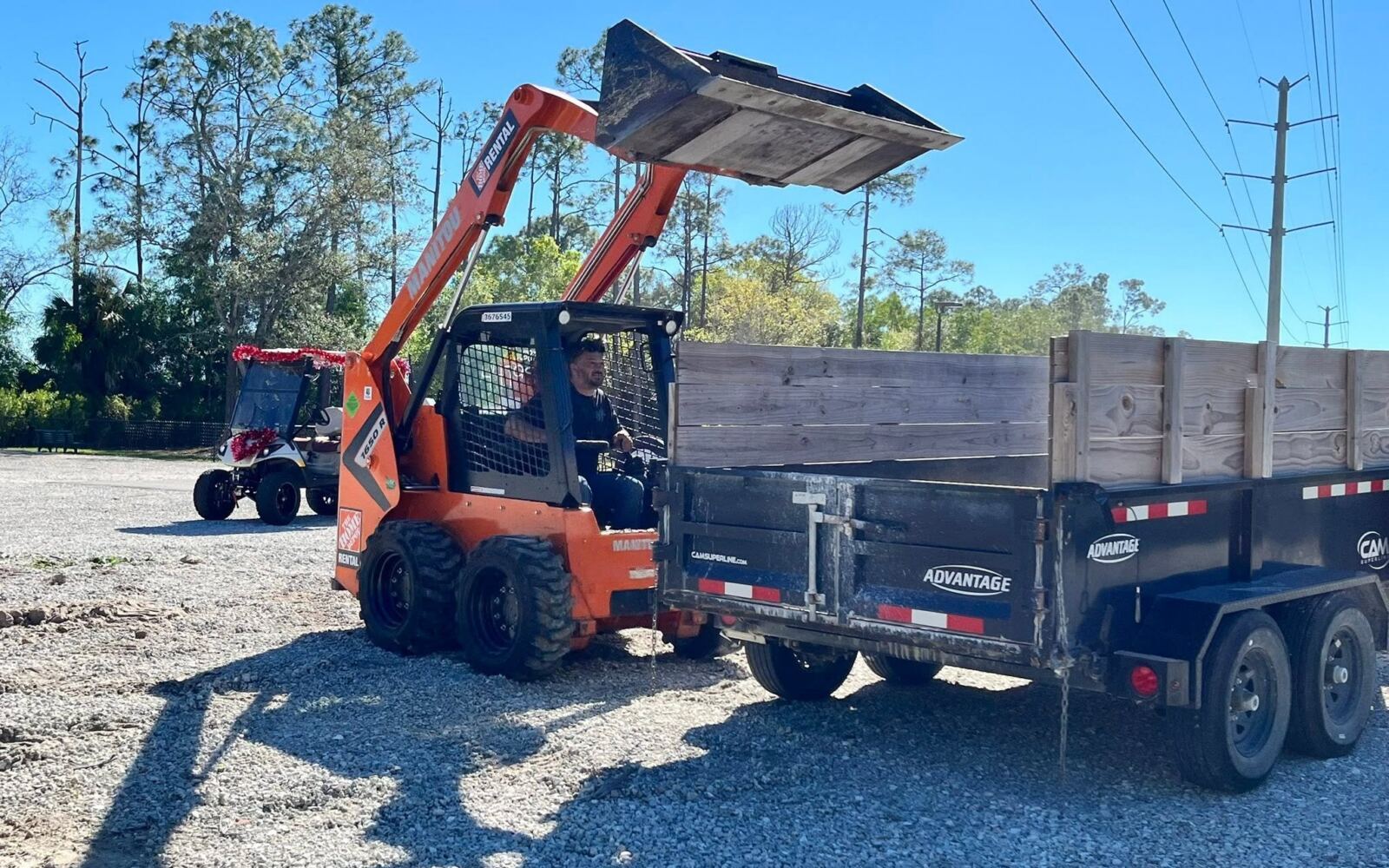 Skid steer loading debris into a dump trailer